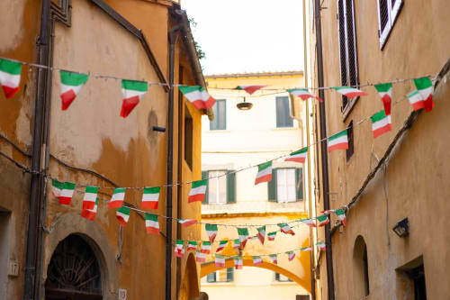 Vicolo italiano a Campagnano di Roma decorato con bandiere tricolori intrecciato tra antichi edifici in pietra