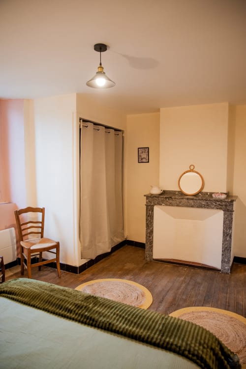 Chambre chaleureuse du gîte Mi Casa Es Su Casa à Carcassonne, avec cheminée, parquet et luminaires suspendus