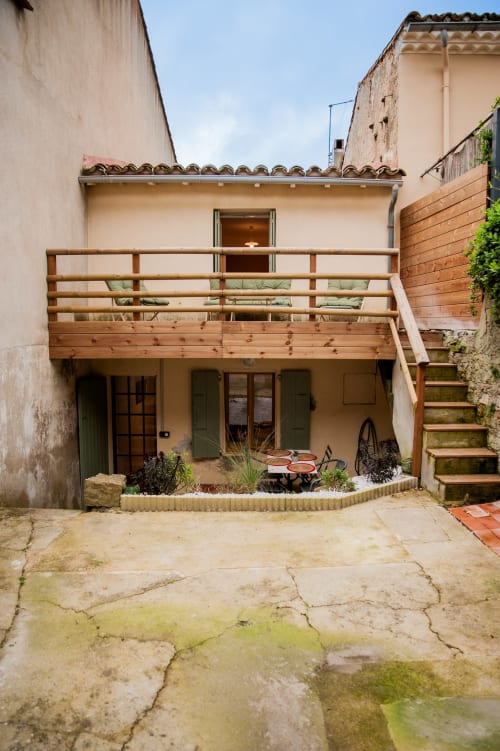 Charmante cour de maison à Carcassonne avec terrasse en bois, plantes en pots et escalier lierre menant à la terrasse supérieure