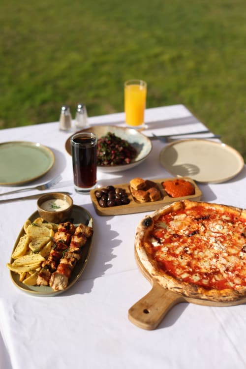Pranzo mediterraneo all'aperto con pizza, spiedini grigliati, olive e succo d'arancia fresco a Travellers Homes, Campagnano