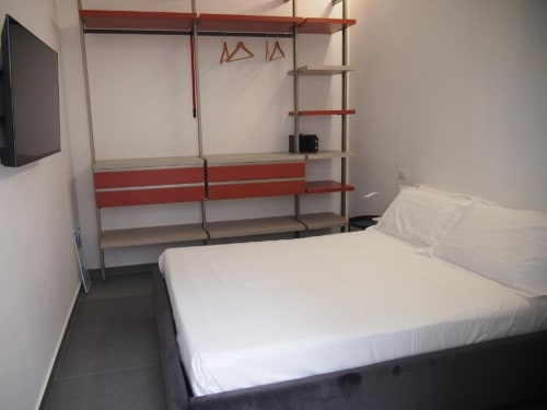 Camera Junior Suite moderna dell'Hotel Vienna di Pesaro con letto bianco, scaffalatura rosso e grigia, TV a schermo piatto e pavimento in piastrelle