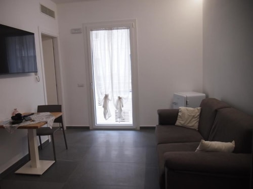 Suite Junior Hotel Vienna a Pesaro con divano marrone, tavolo da pranzo, angolo cottura, TV a schermo piatto e porta-balcone in vetro