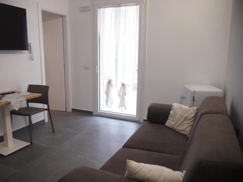 Moderna Junior Suite dell'Hotel Vienna a Pesaro con divano marrone, zona pranzo, porte verso il balcone e TV a schermo piatto