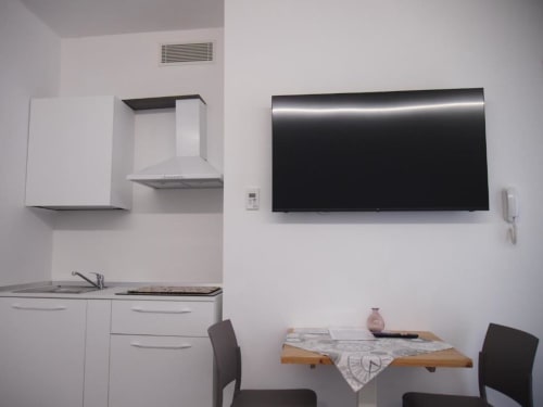 Moderna Junior Suite con angolo cottura all'Hotel Vienna Pesaro: TV schermo piatto, tavolo da pranzo e armadiatura bianca