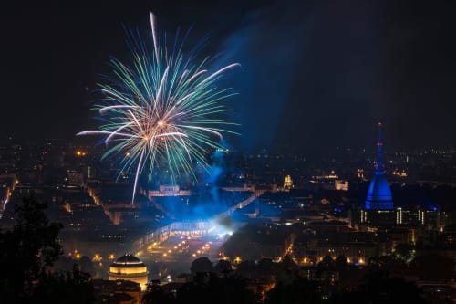 Skyline di Torino di notte con fuochi d'artificio, la Mole Antonelliana illuminata in blu, celebrazioni vicino a Roma