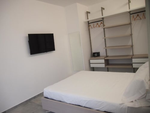 Camera junior suite moderna dell'Hotel Vienna a Pesaro con TV a parete, letto e libreria integrata in legno