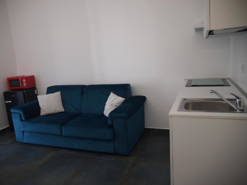 Zona living della Junior Suite all'Hotel Vienna Pesaro con divano letto blu e angolo cottura con microonde e lavello