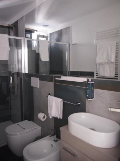 Bagno moderno dell'Hotel Vienna Pesaro con vasca bianca, toilet, cabina doccia e dettagli in piastrelle nere
