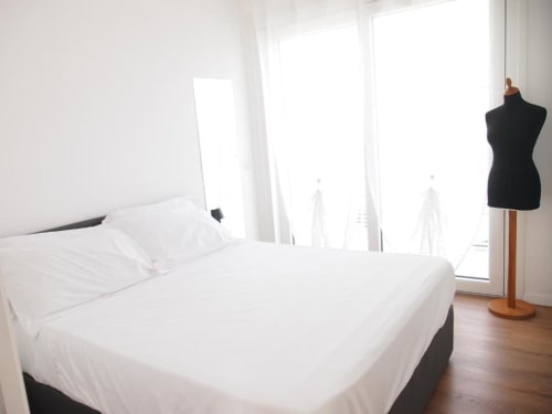 Helles Superior-Zimmer im Hotel Vienna in Pesaro mit weißem Bett, Balkonblick auf Stadt und Meer, Holzböden und