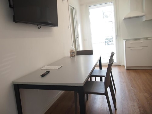 Moderner Speisebereich der Hotel Vienna Superior Suite in Pesaro mit langem Tisch, dunklen Stühlen, Flachbildfernseher und Balkon