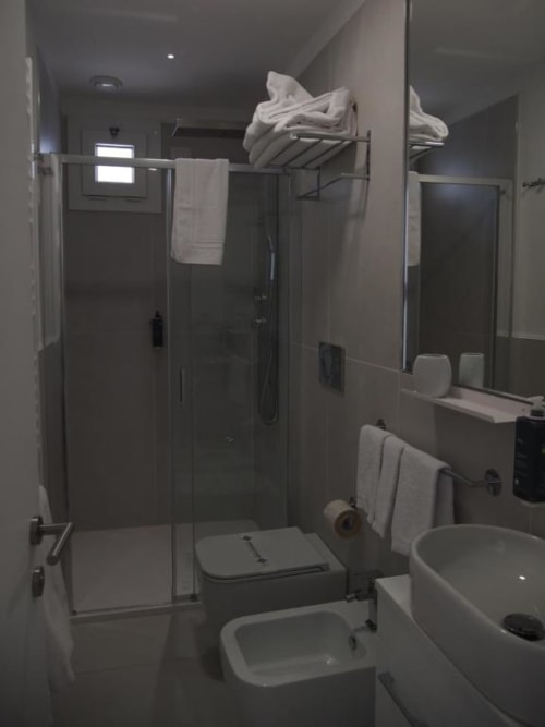 Modernes Badezimmer in der Hotel Vienna Superior Suite, Pesaro, mit Glasschiebetür, Bidet, Toilette und weißen Handtüchern