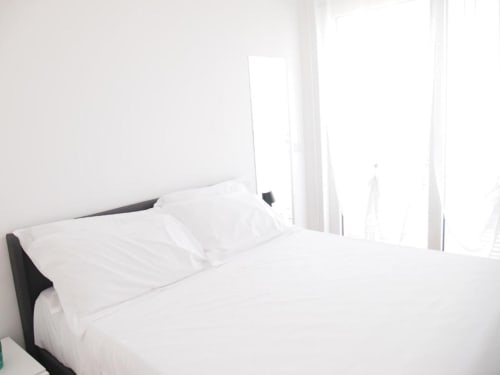 Helles Superior Suite Schlafzimmer im Hotel Vienna Pesaro mit weißer Bettwäsche, schwarzem Kopfteil und Meerblickfenstern