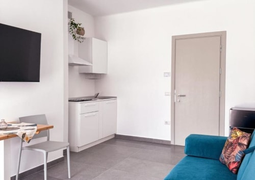 Suite Superiore moderna all'Hotel Vienna di Pesaro con angolo cottura, divano letto blu, TV e arredi contemporanei
