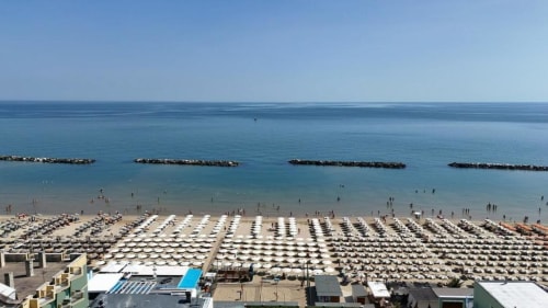 Vista aerea della spiaggia di Pesaro con ombrelloni e bagnanti lungo la costa dell'Adriatico