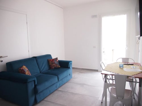 Soggiorno con divano blu e zona pranzo nella Suite Superior di Hotel Vienna a Pesaro, con accesso a balcone luminoso e vista città