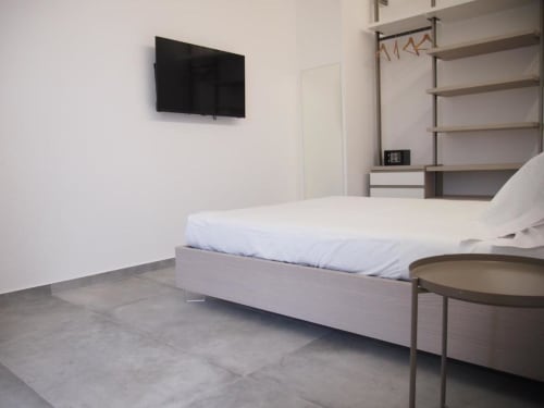 Camera Superior moderna dell'Hotel Vienna con letto, TV a parete, angolo cottura e scaffali a Pesaro