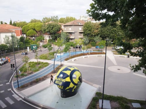 Piazza moderna a Pesaro con scultura gialla e blu, circondato dall'Hotel Vienna e dall'architettura urbana