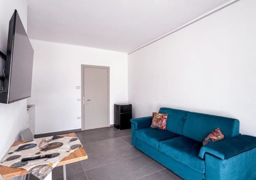 Suite Superior moderna dell'Hotel Vienna a Pesaro con divano blu, tavolo da pranzo, TV a schermo piatto e angolo cottura