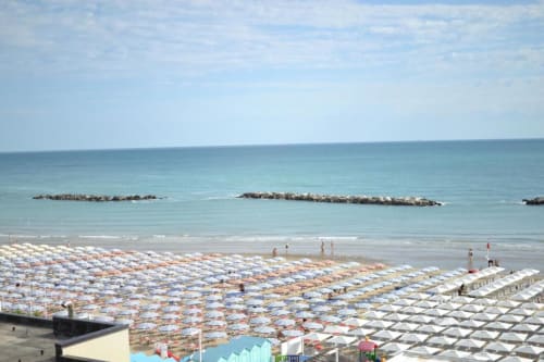 Spiaggia di Pesaro con ombrelloni colorati, sdraio e vista mare dalla terrazza dell'Hotel Vienna