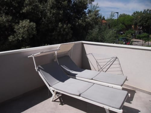 Terrazza panoramica dell'Hotel Vienna a Pesaro con lettini bianchi e pergolato, vista sulla città circondata da alberi.