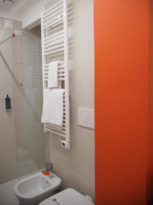 Bagno moderno dell'Hotel Vienna Pesaro con scaldasalviette bianco, parete color arancio, lavabo, bidet e box doccia