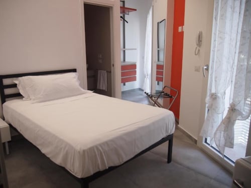 Camera moderna dell'Hotel Vienna a Pesaro con letto matrimoniale, parete rossa decorativa, bagno interno e balcone con porta in vetro