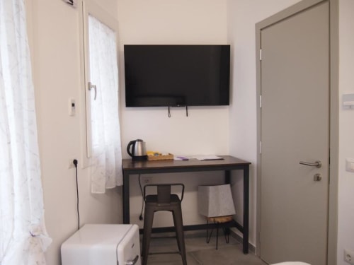 Camera moderna dell'Hotel Vienna a Pesaro con scrivania, TV a parete, bollitore elettrico e arredamenti minimalisti