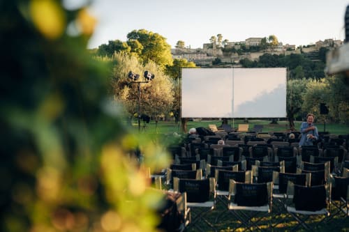 Outdoor cinema screening at Le Domaine du Fortin in Ménerbes, with guests seated in amphitheater chairs facing a large white