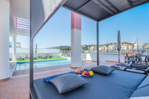 Lounge à beira-mar da Villa Odyssey com espreguiçadeiras, piscina e vista para a marina em Albufeira