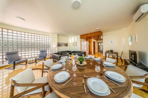 Sala de jantar da Villa Odyssey em Albufeira com mesa redonda de madeira, talheres e mobiliário moderno