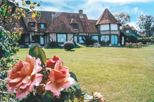Des roses roses encadrent le manoir à colombages de La Girelle avec ses jardins soignés à Honfleur, France