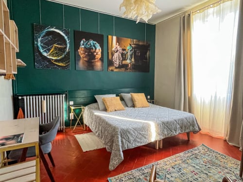 Chambre spacieuse à La Maison Gerval B&B à Bédoin avec murs bleu-vert, lit queen-size, sol en terre cuite rouge et galerie de cadres