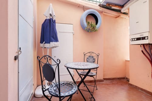 Cozy patio at Casa Scola Loano with bistro table, chairs, blue umbrella, and potted plant in Loano