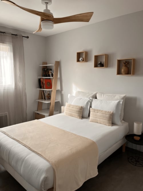 Chambre moderne et lumineuse au Gîte la Villa des Falaises du Lot avec literie blanche, ventilateur de plafond en bois et étagères murales.