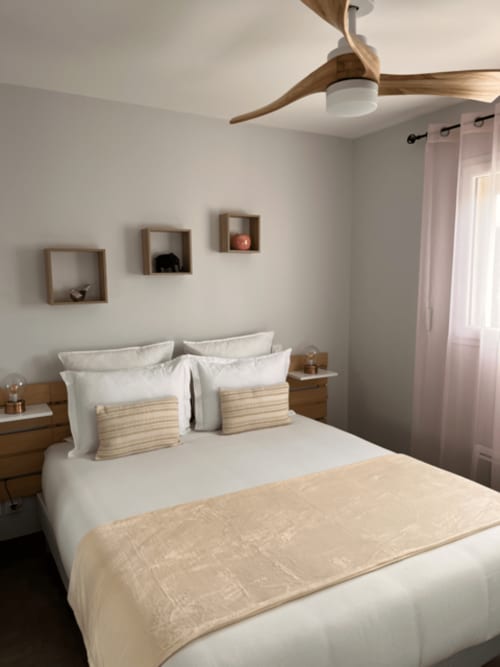 Chambre moderne à la Gîte la Villa des Falaises du Lot avec ventilateur de plafond en bois, literie blanche et étagères flottantes