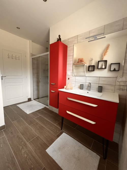 Salle de bain moderne avec meuble vasque rouge, douche à l'italienne et revêtement aspect bois au Gîte la Villa des Falaises du Lot