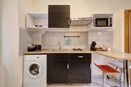 Modern kitchen at Casa Scola Loano with black cabinets, wood countertops, stainless steel appliances, and breakfast bar