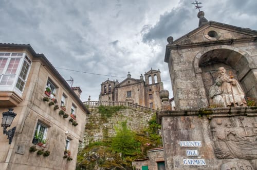 Historic stone buildings and church in Padrón, Spain, featuring traditional architecture with flowering window boxes