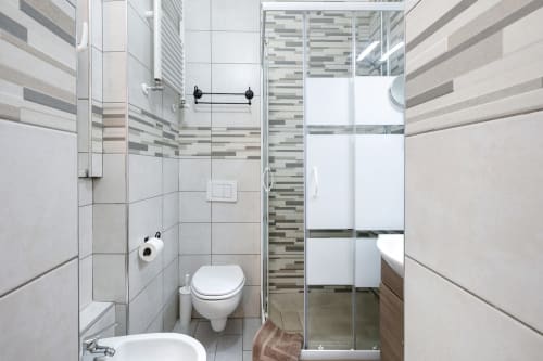 Modern bathroom at Casa Scola Loano B&B in Loano with striped tile accents, glass shower enclosure, and white fixtures