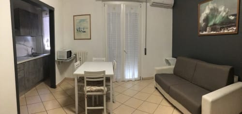 Casa Scola Loano BnB studio apartment with kitchen, dining table, sofa, and bathroom in Loano, Italy