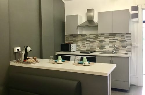 Modern kitchen area at Casa Scola Loano B&B in Loano with white cabinetry, geometric backsplash, and island counter