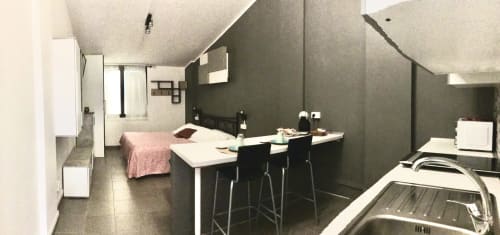 Modern studio at Casa Scola Loano with kitchen, workspace desk, bed, and dark accent wall