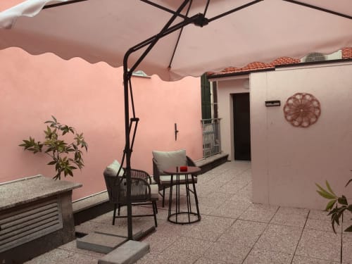 Casa Scola Loano terrace with pink walls, umbrella, lounge chairs, and potted plants in Loano, Italy