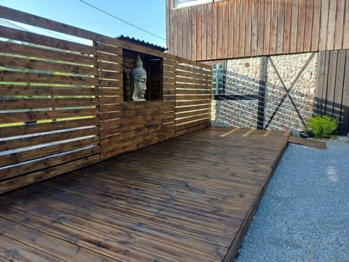 Modern wooden deck terrace at Le gite des mousquetaires in Lanne en Baretous with Buddha statue and stone walls