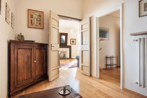 Corridoio luminoso nell'appartamento Casa Clara ad Assisi, con porte in legno, mobili antichi e pavimenti in parquet che conducono alla camera da letto