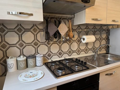 Cucina moderna nell'appartamento Casa Clara ad Assisi, con piastrelle geometriche, piano cottura a gas, lavello e utensili sospesi