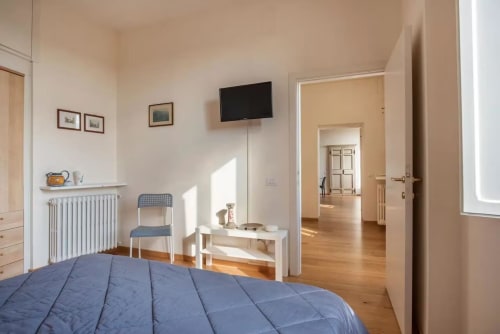 Camera luminosa a Casa Clara, appartamento ad Assisi con letto con biancheria blu, TV a parete e pavimenti in legno