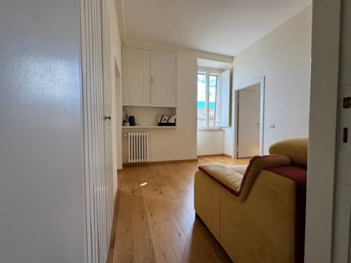 Soggiorno dell'appartamento Casa Clara ad Assisi con pavimenti in legno, divano in pelle color cuoio e moderni comfort inclusi TV e