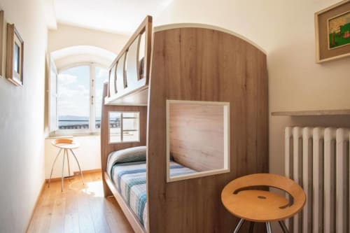 Camera accogliente di Casa Clara ad Assisi con letto a castello in legno, scrivania con vista sulla città e termosifone
