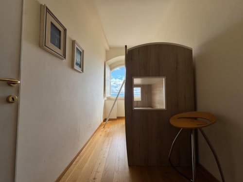 Corridoio moderno nella dependance di Casa Clara, Assisi, con pavimentazione in legno, struttura in legno scuro e finestra con blu
